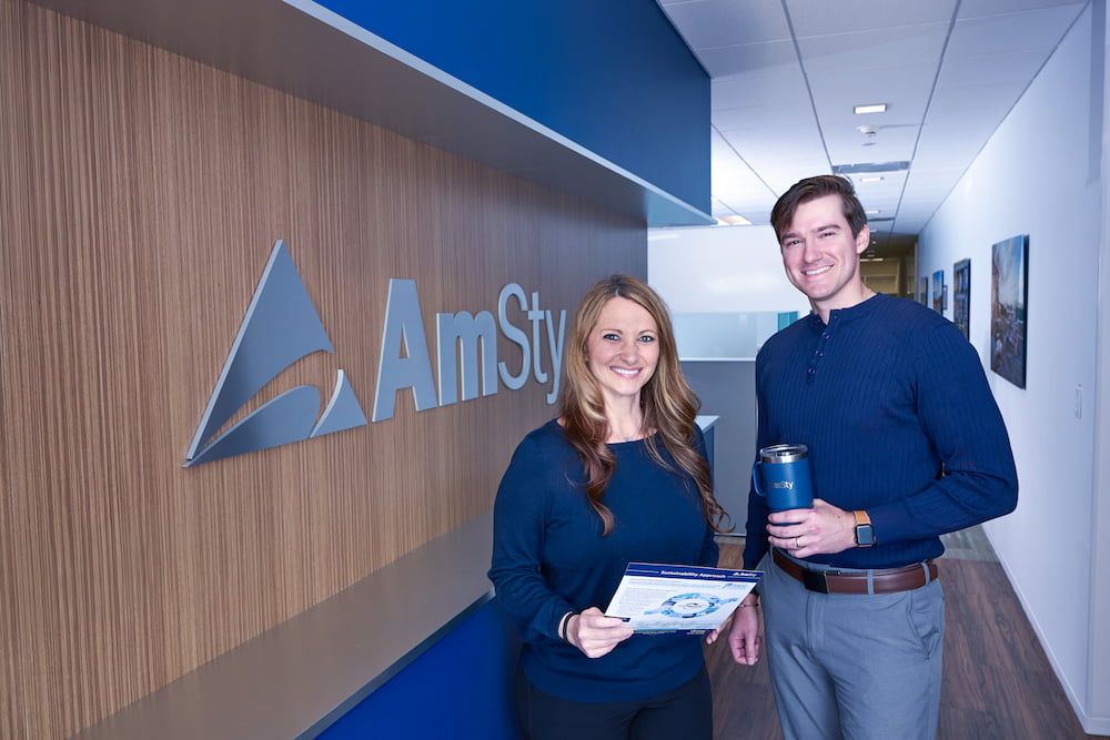 A man and woman stand in a hallway looking at documents