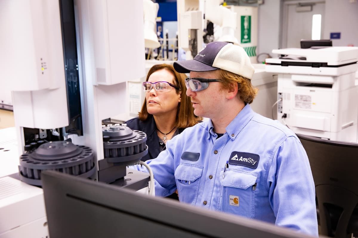 Woman and man wearing safety glasses examine a screen in a laboratory