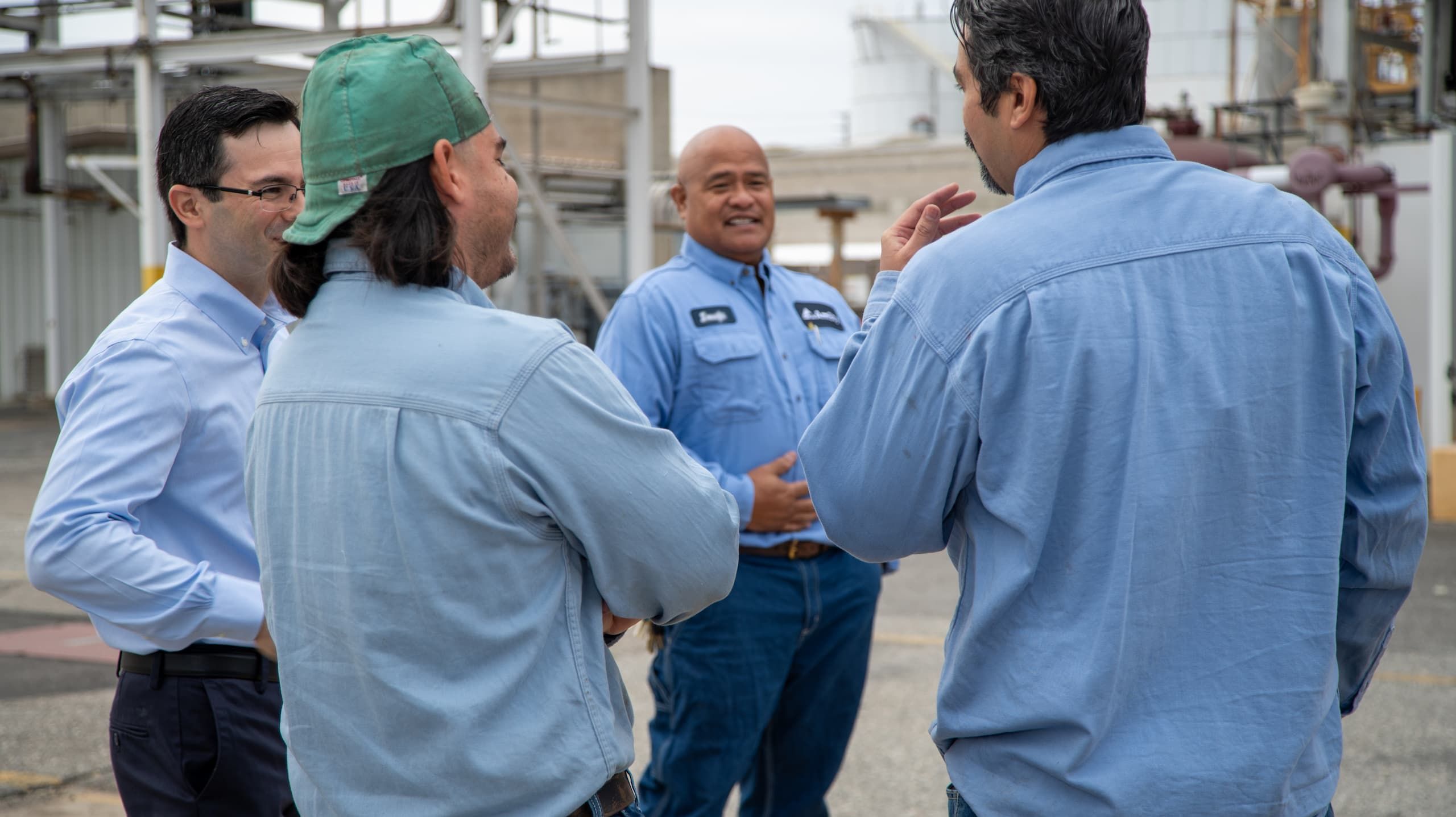 A group of male employees in uniforms stand outside smiling and laughing